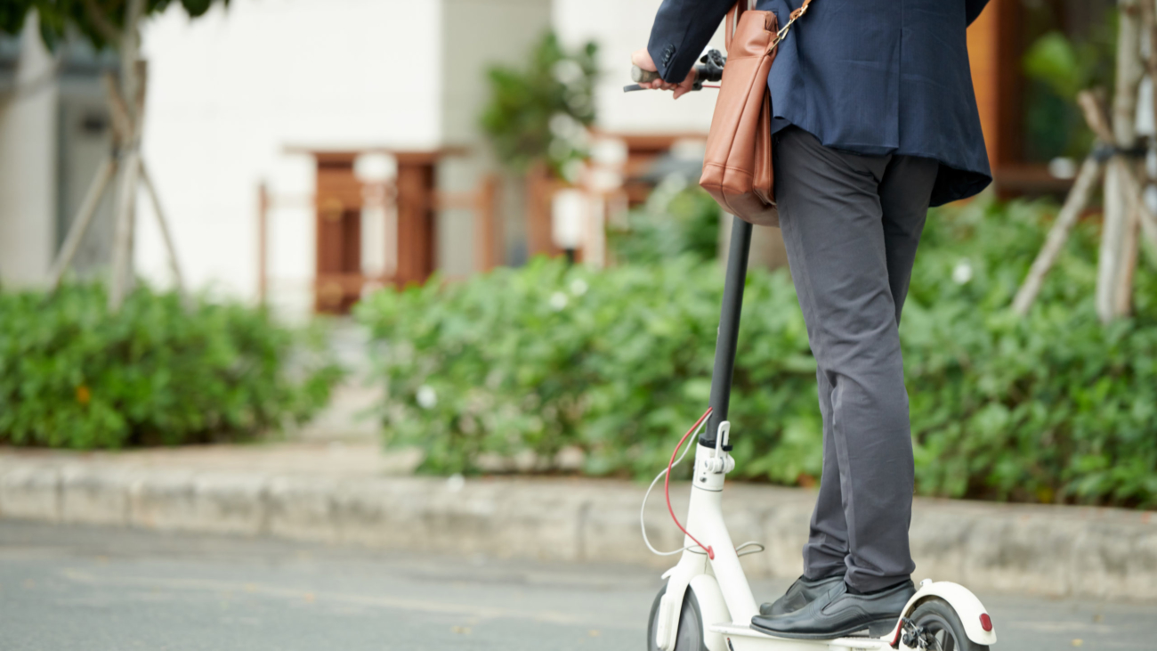 Cropped image of entrepreneur or student riding to work on electric kick scooter