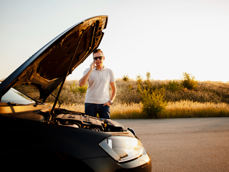 Coche averiado en carretera bajo el sol durante un viaje de verano