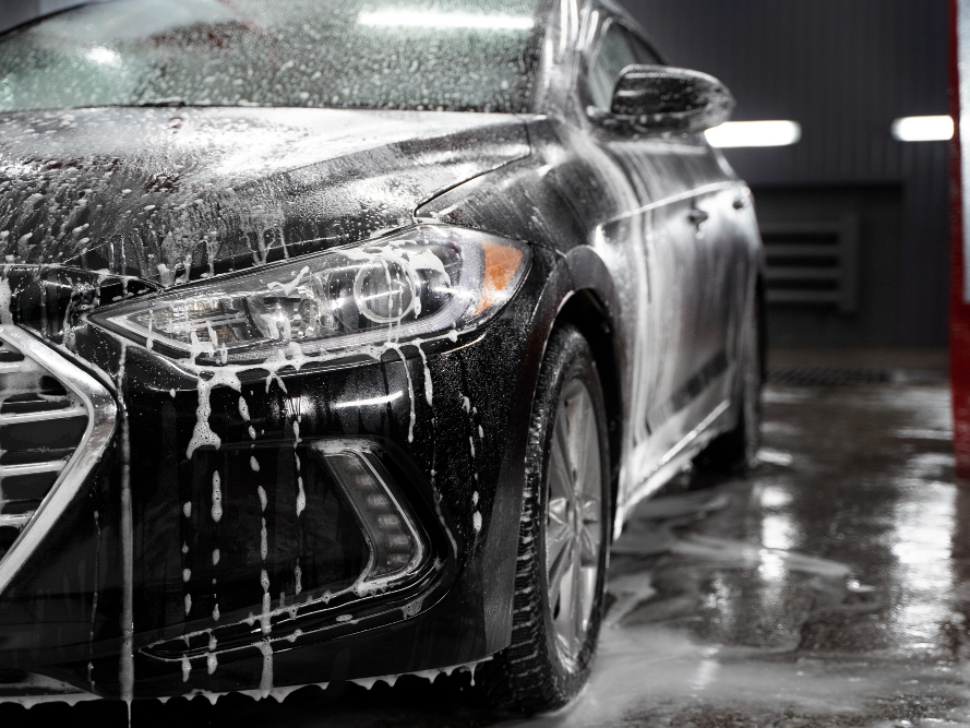 Detalle de lavado de coche con productos adecuados para cuidar la pintura.