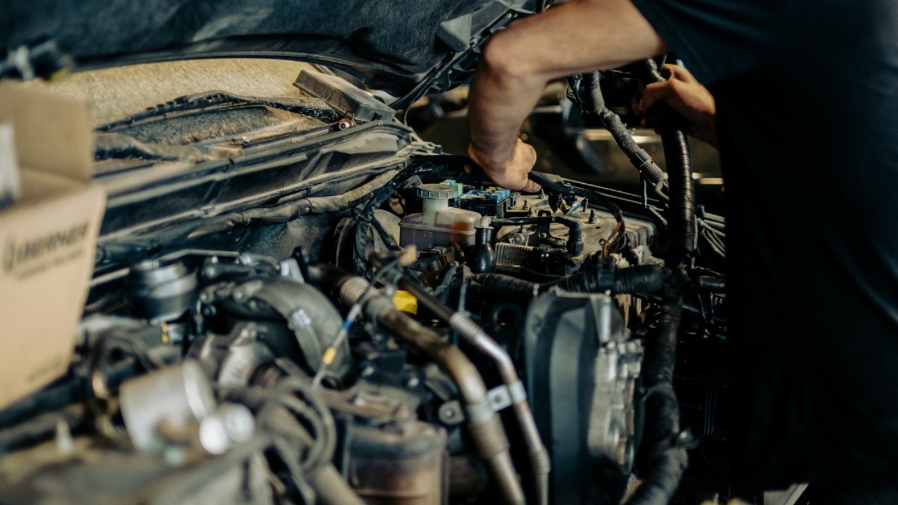 Técnico revisando el motor de un coche en busca de ruidos anómalos.