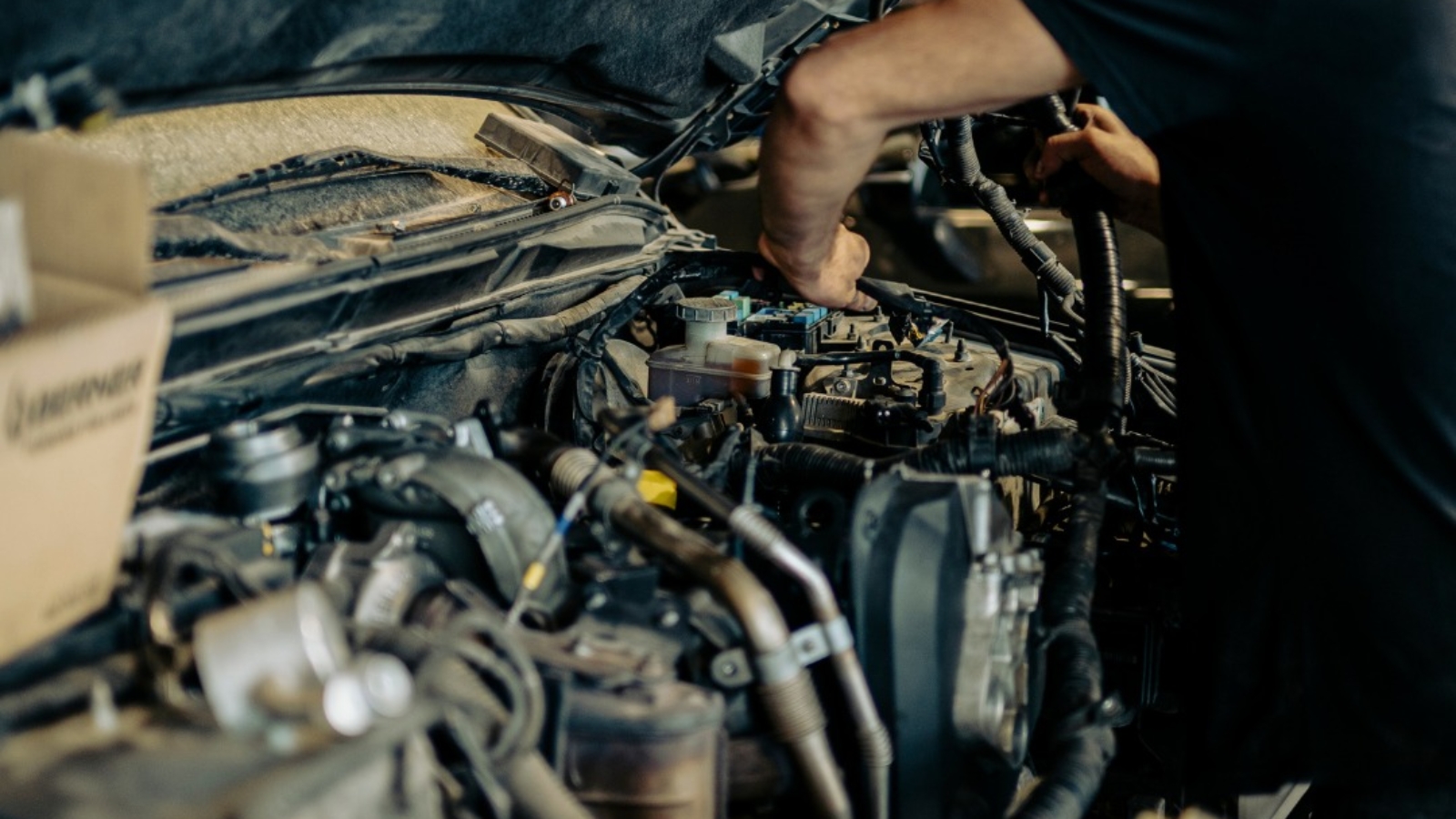 Técnico revisando el motor de un coche en busca de ruidos anómalos.