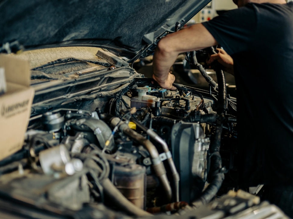 Técnico revisando el motor de un coche en busca de ruidos anómalos.