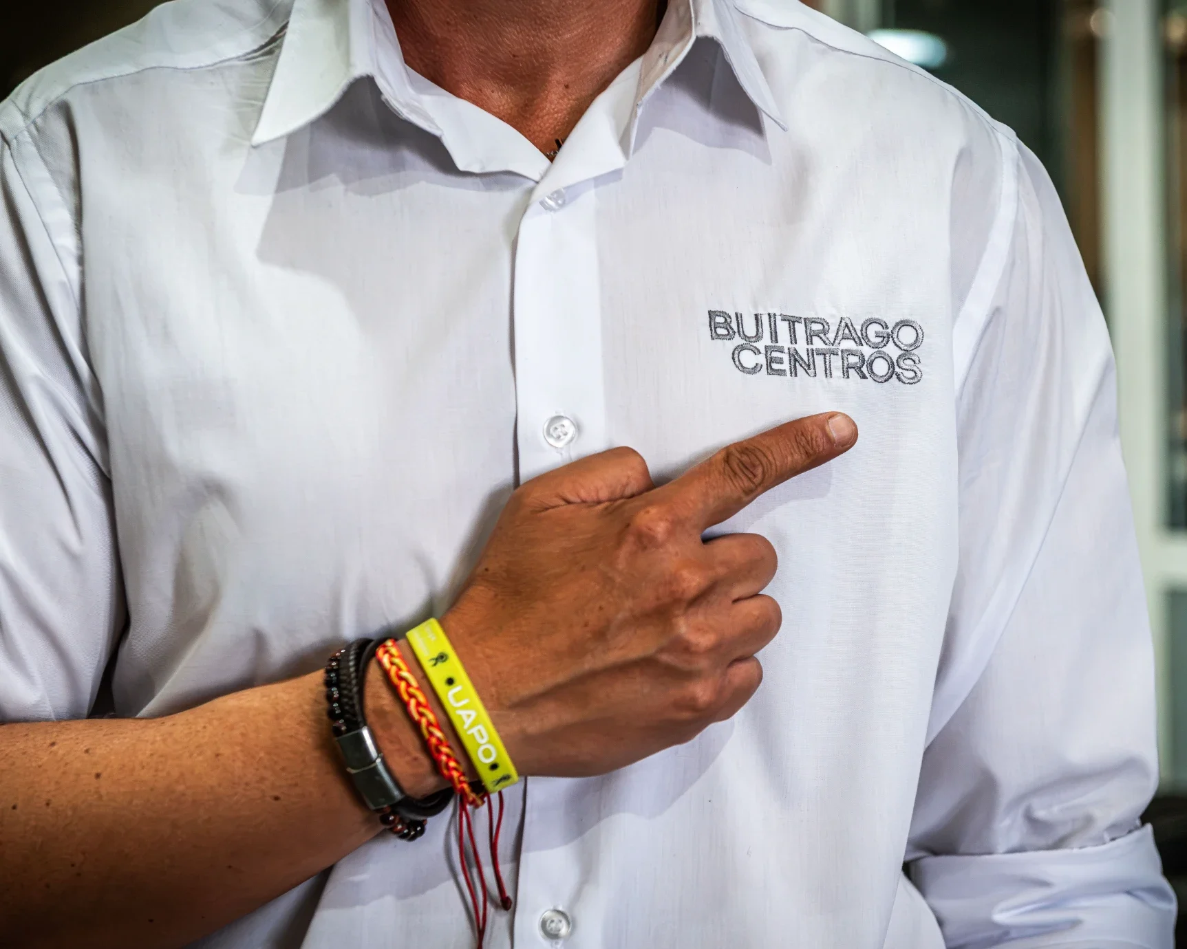 Persona señalando el logo bordado de Buitrago Centros en su camisa